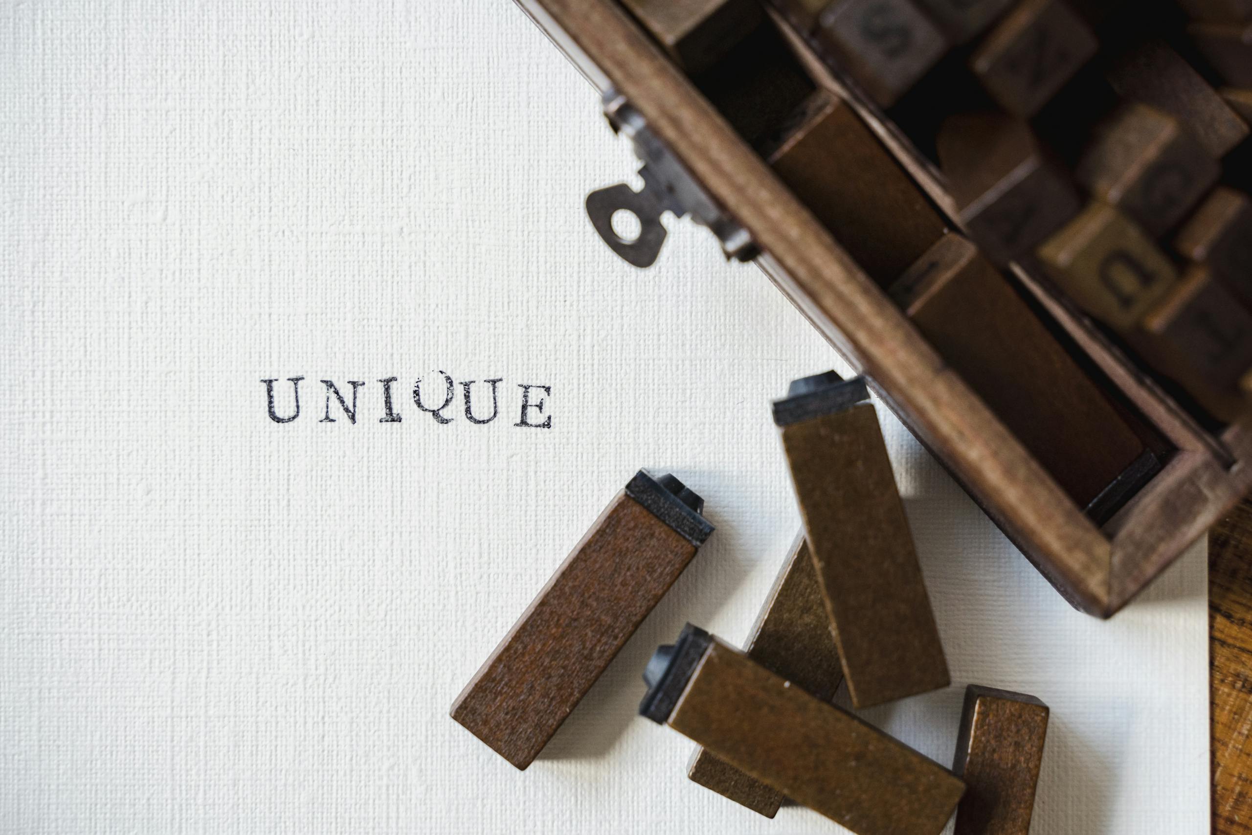 Wooden blocks spelling 'UNIQUE' stamped on textured white canvas